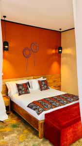 a bedroom with a large bed with an orange wall at Enjipai Ngorongoro Lodge in Karatu +6 photos