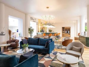 eine Lobby mit blauen Sofas, Stühlen und Tischen in der Unterkunft Mercure Brussels Centre Rogier in Brüssel