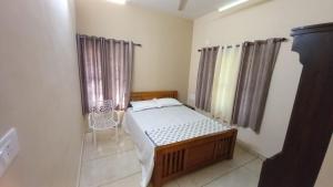 a bedroom with a bed and a chair in it at Kodikkakkam Homestay in Kappil