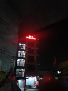 a tall building with a red sign on it at night at Hotel Malik Palace in Noāmundi
