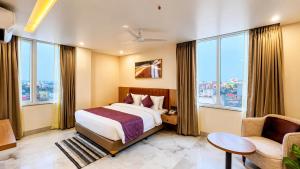 a hotel room with a bed and a couch and windows at Vaishnavi Beacon Hotel Patna in Patna