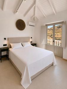 a white bedroom with a white bed and a desk at Dryope Luxury Living in Dhriopís