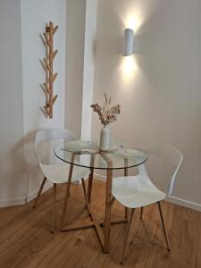 a glass table with two chairs and a vase with flowers at Studio de charme - Centre Vienne - Proche gare in Vienne