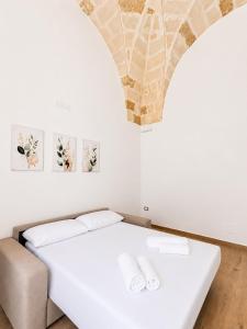 a white bedroom with a bed and a chair at Palazzo Solera in Casarano