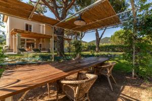 a wooden table and chairs under a wooden pergola at Charme Villa La Vela - Goelba in Lacona