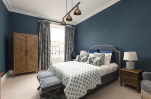 a blue bedroom with a bed and a chair at West End Townhouse in Edinburgh