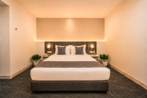 a large bed in a room with two plants at S by Z Hotels, HSR in Bangalore