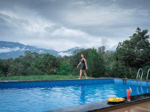 a woman walking by a swimming pool at Velvet Revive Munnar in Munnar