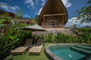 two chairs and an umbrella next to a swimming pool at Velonia Iseh in Sidemen