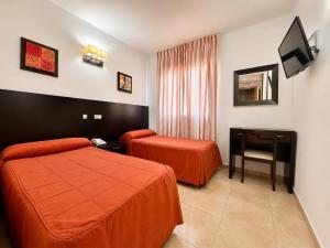 a hotel room with two beds and a television at Hostal Goyma III in San Fernando de Henares