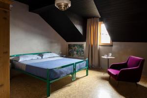 a bedroom with a bed and a purple chair at Herbighe Retreat in Asiago