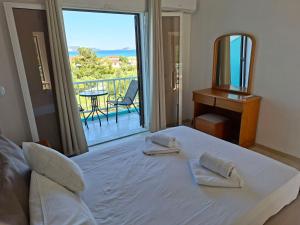 a bedroom with a bed with towels on it with a balcony at Cleopatra Apartments in Laganas