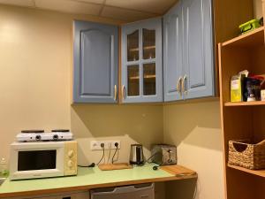 a kitchen with blue cabinets and a microwave on a counter at Jaani 2 Apartment in Pärnu +11 photos