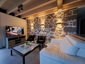 a living room with a white couch and a stone wall at La remise de Saussenigoutte in Cornimont