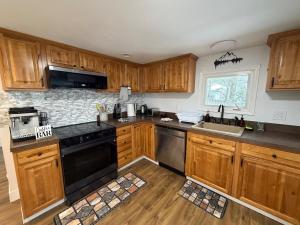 a kitchen with wooden cabinets and a black dishwasher at Poconos Hideaway in Greentown