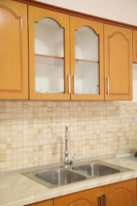 a kitchen with a sink and wooden cabinets at Prim Guest House in Këlcyrë