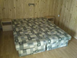 a large bed in a room with wooden walls at Privat 107 in Pavčina Lehota