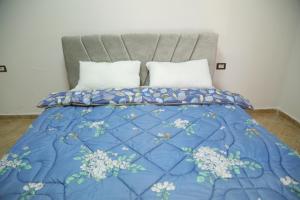 a bed with a blue comforter and white pillows at Prim Guest House in Këlcyrë +24 photos