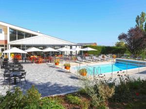 a resort with a pool and tables and chairs and umbrellas at ibis Styles Nancy Sud in Houdemont