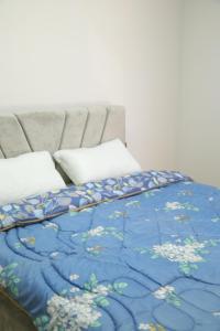 a bed with a blue blanket and white pillows at Prim Guest House in Këlcyrë