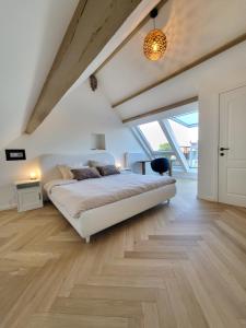 a bedroom with a large white bed and wooden floors at Castle-grounds house with rooftop view & jacuzzi in Ghent
