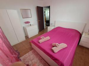 a bedroom with a pink bed with two towels on it at Casa Vale Frio in Calheta
