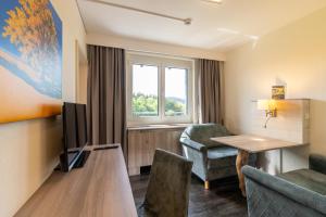 a hotel room with a table and chairs and a television at Hotel Am Bühl in Eibenstock