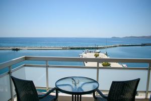 a table and chairs on a balcony overlooking the water at Hotel ALS KARYSTOS in Karistos