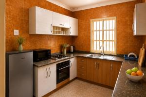 a kitchen with white cabinets and a stove and a sink at Kays Royal Suite in Isasi