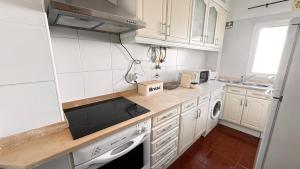 a small kitchen with white cabinets and a sink at Cabana Fersan in Cabanas de Tavira