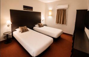 a hotel room with two beds and a television at Hôtel Restaurant Akena Bordeaux Sud - La Brède in La Brede