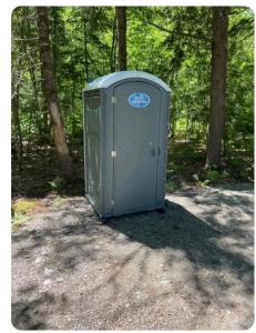 a portable toilet sitting in the middle of a forest at Flatrock on the River Topknot in Frankfort
