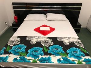 a bed with a red pillow and blue flowers on it at Disney golden house in Magny-le-Hongre