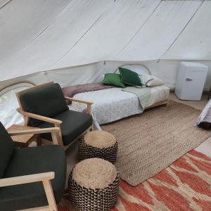 a bedroom with a bed and two chairs in a tent at Flatrock on the River Topknot in Frankfort