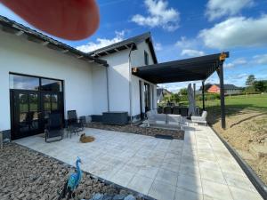 a house with a patio and a bird on the ground at De Horizon in Bullange