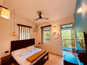 a bedroom with a bed and a large window at Bijou Guest House in Baga +8 photos