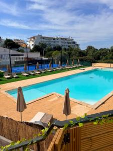 a large swimming pool with umbrellas and chairs at Marachique Beach Flat in Alvor +15 photos