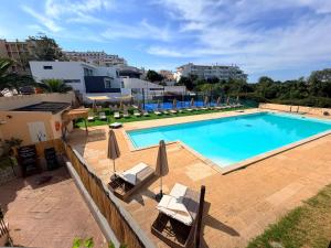 a large swimming pool with chairs and umbrellas at Marachique Beach Flat in Alvor