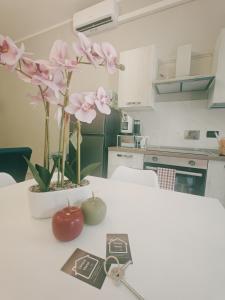 ein weißer Tisch mit einer Vase mit rosa Blumen darauf in der Unterkunft Dimora Marsè - Indipendente con area esterna privata in Moncalieri