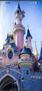 a disney castle building with a clock on it at Disney golden house in Magny-le-Hongre