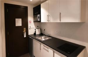 a kitchen with white cabinets and a sink at Résidence Les Alizés Bordeaux Sud - La Brède in La Brede +4 photos