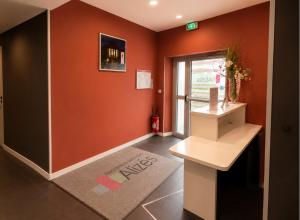 a hallway with orange walls and a desk and a window at Résidence Les Alizés Bordeaux Sud - La Brède in La Brede