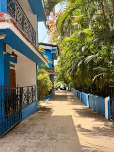 a street in a town with blue buildings and palm trees at Bijou Guest House in Baga