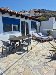 a patio with a table and chairs and a building at Nektaria on the Beach in Fournoi