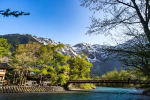 a bridge over a river with mountains in the background at Tabist Kazeyuki in Takayama