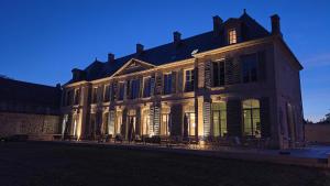 a large building with lights illuminating the front of it at Château de l'Abbatiale in Braine