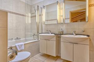 a bathroom with two sinks and a tub and a toilet at Apartment Brunnen - GRIWA RENT AG in Grindelwald +12 photos