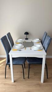 a white table with chairs and plates on it at Royal Apartment in Rumia