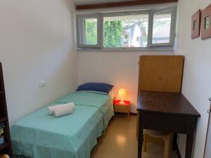 a bedroom with a bed and a desk and a window at Villa Tamerici - Garden & Parking in Lignano Sabbiadoro