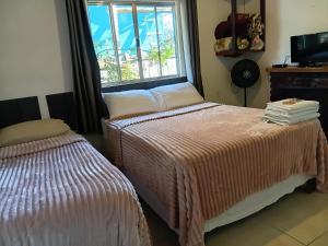 a bedroom with two beds and a window at Suítes portal do bosque in Visconde De Maua